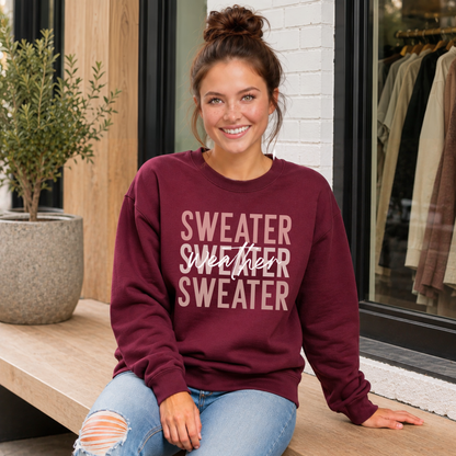 Woman sitting on a porch wearing a maroon “Sweater Weather Sweater” crewneck sweatshirt and jeans.