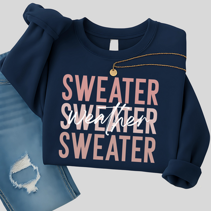 Navy blue Sweater Weather sweatshirt folded with gold necklace, styled with jeans. A cozy unisex fall pullover perfect for women’s casual outfits and winter layering.