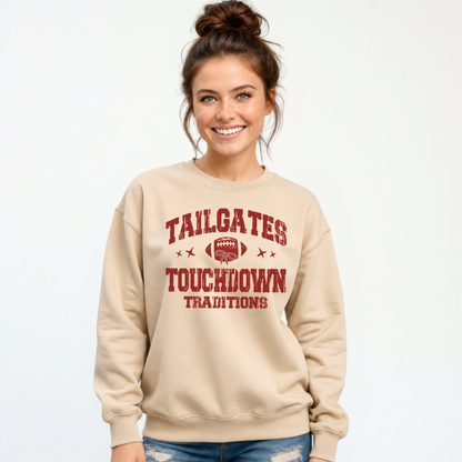 Sand crewneck sweatshirt featuring the Tailgates & Touchdown Traditions graphic, worn by a smiling woman in jeans.