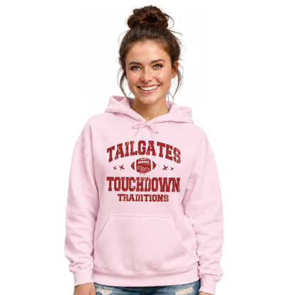 Smiling woman wears a light pink hoodie printed with the Tailgates & Touchdown Traditions football graphic.