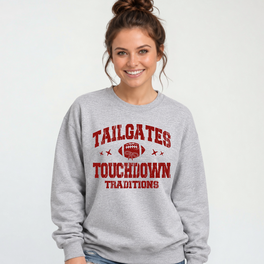 Sports gray crewneck sweatshirt with a red football and Tailgates & Touchdown Traditions wording, modeled with distressed jeans.