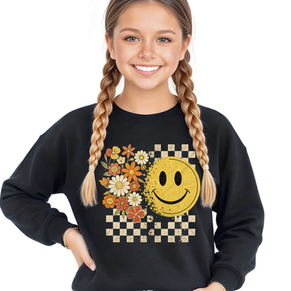 Teen girl wearing a Black fall smiley face sweatshirt with floral and checkerboard design