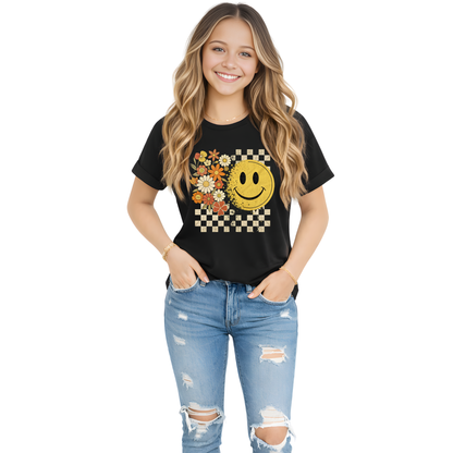 Teen girl wearing a black fall t-shirt with a smiley face design and ripped jeans on a white background