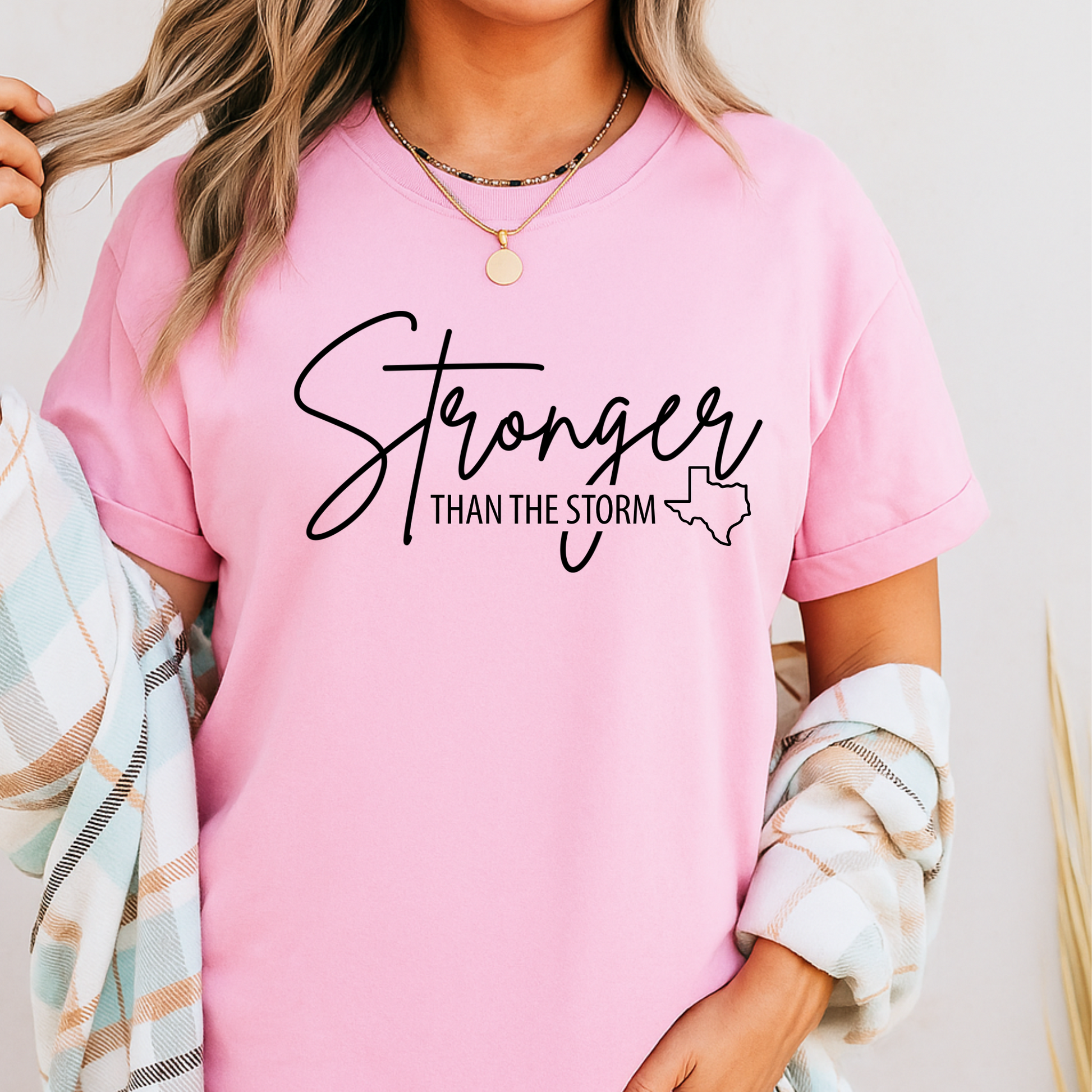Model in light pink "Stronger Than the Storm" graphic T-shirt with Texas outline, Christian faith and Texas flood relief shirt for women, rolled sleeve fit.