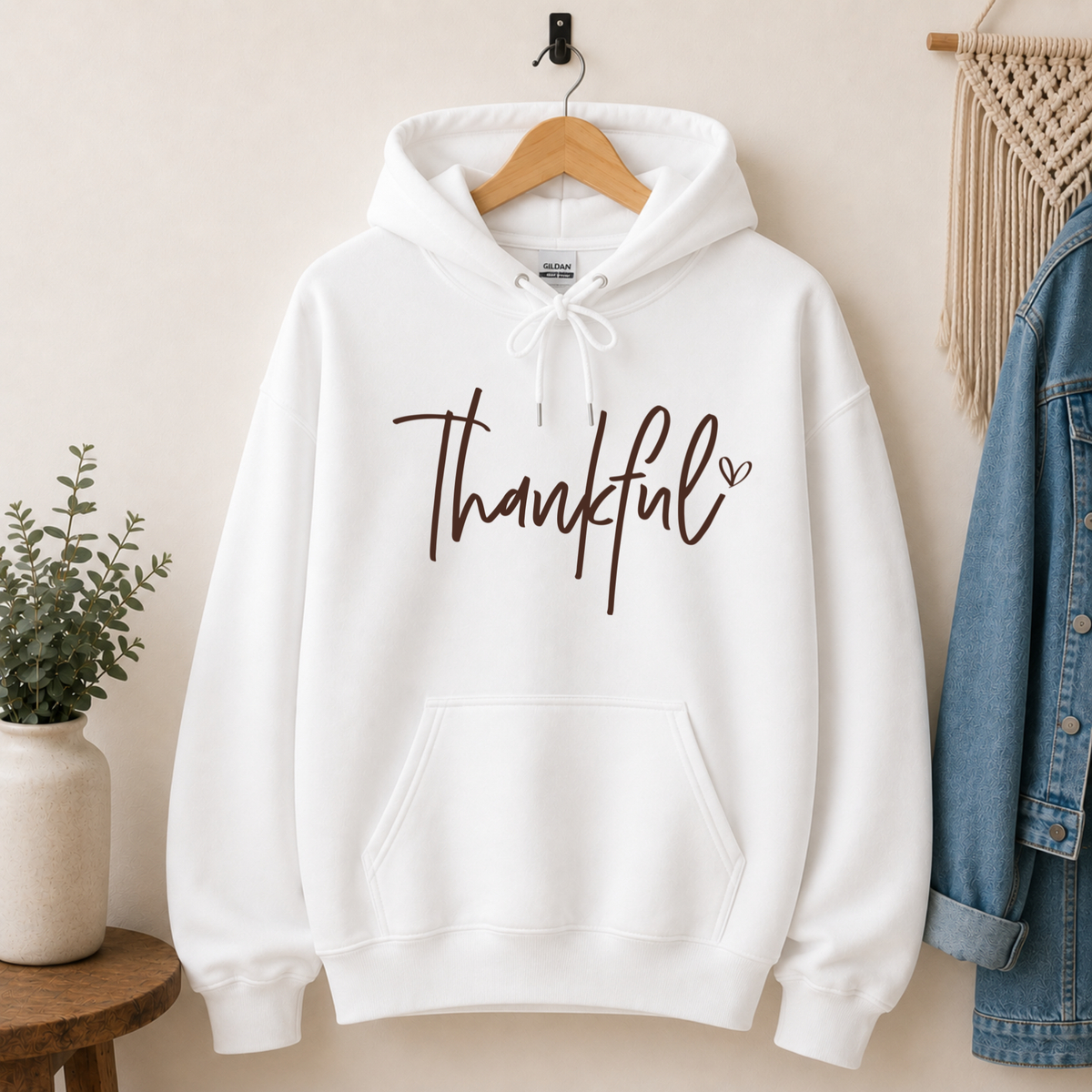 White pullover hoodie with a Thankful script design displayed on a hanger