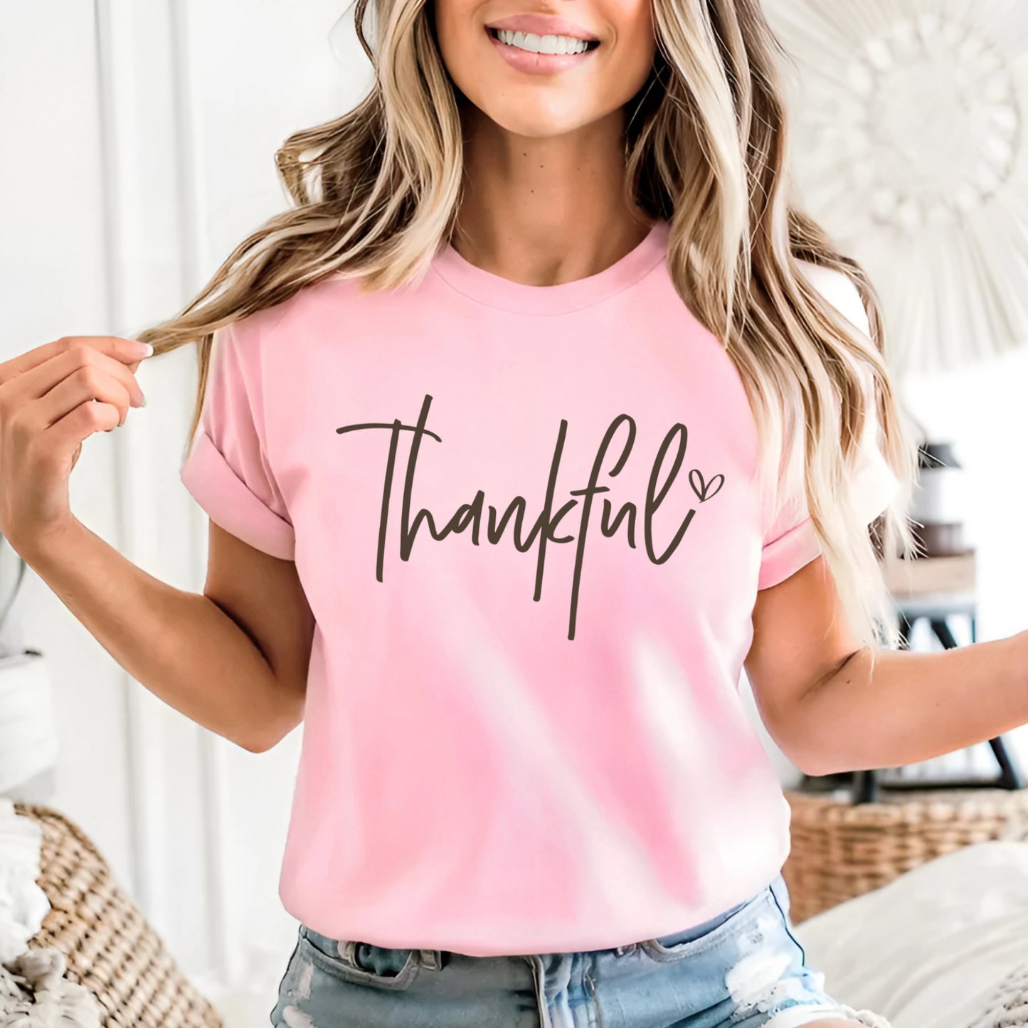 Woman wearing pink “Thankful” T-shirt with jeans, smiling