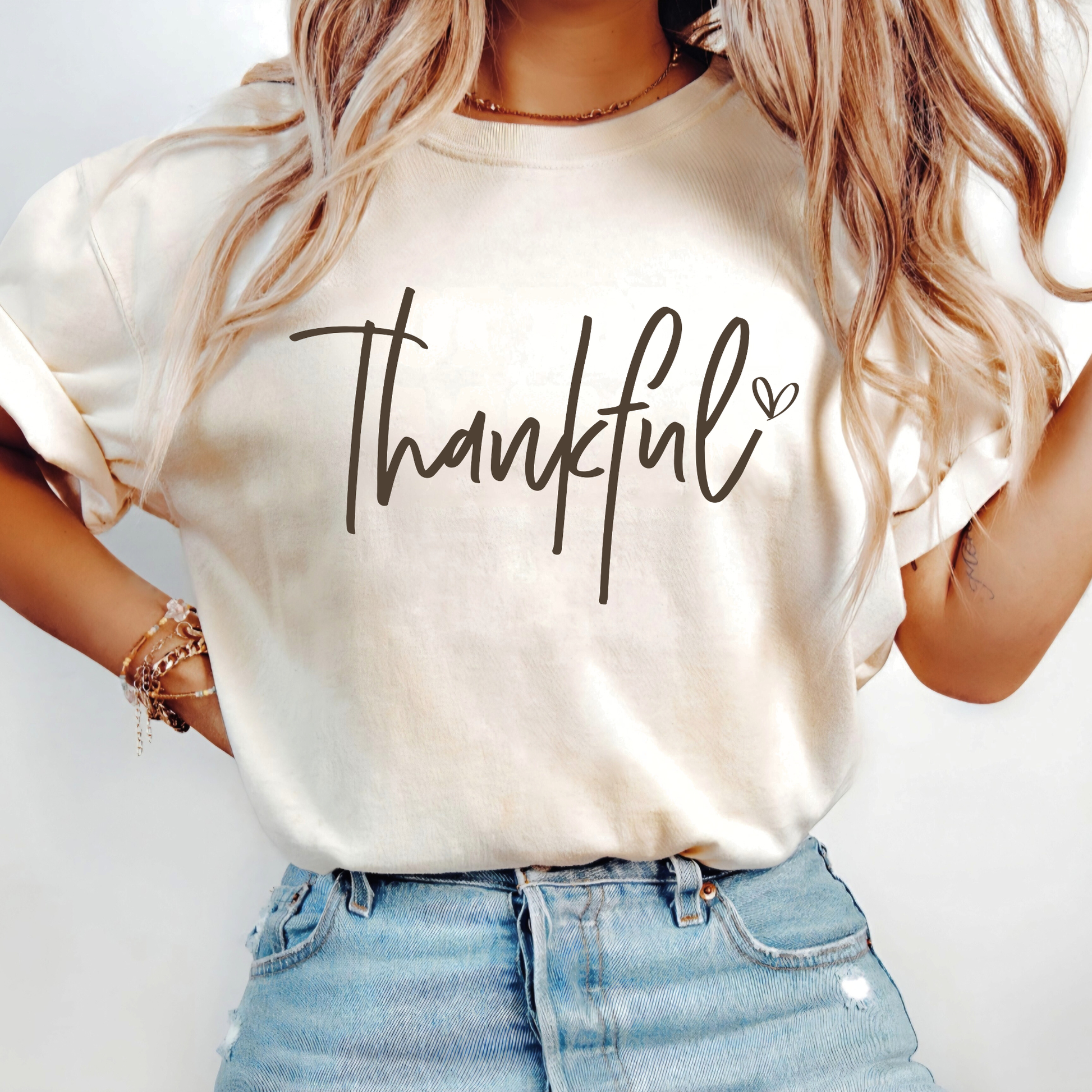 Woman wearing cream “Thankful” tee styled with casual fall outfit