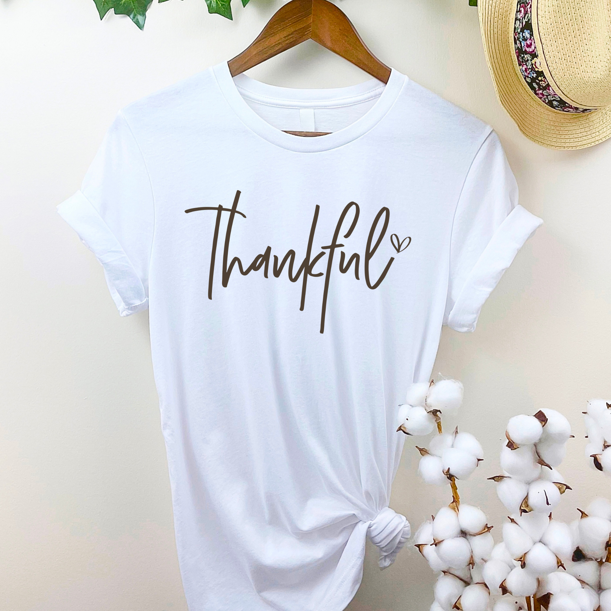 White “Thankful” shirt hanging on wooden hanger for Thanksgiving