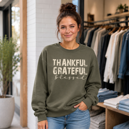 Woman wearing a military green sweatshirt with distressed Thankful Grateful Blessed text inside a clothing boutique.