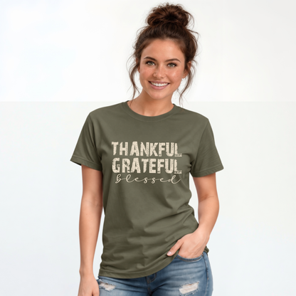 Woman wearing a military green T-shirt with distressed Thankful Grateful Blessed lettering on a plain white background.