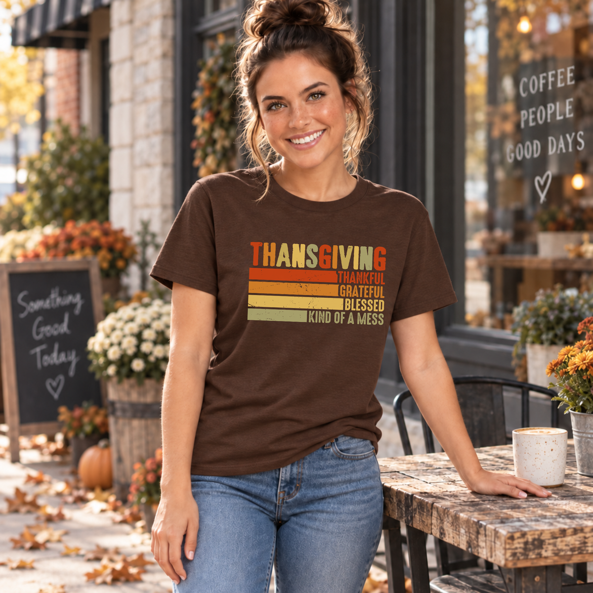 Woman wearing a brown T-shirt with retro Thanksgiving Kind of a Mess design beside an outdoor cafe table in fall.