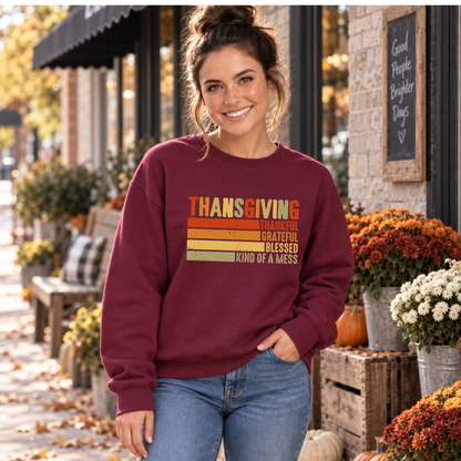 Woman wearing a maroon sweatshirt with retro Thanksgiving Kind of a Mess design beside fall flowers and pumpkins.