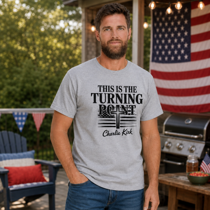 Man wearing a sports gray T-shirt with black This Is the Turning Point cross graphic in a patriotic backyard setting.