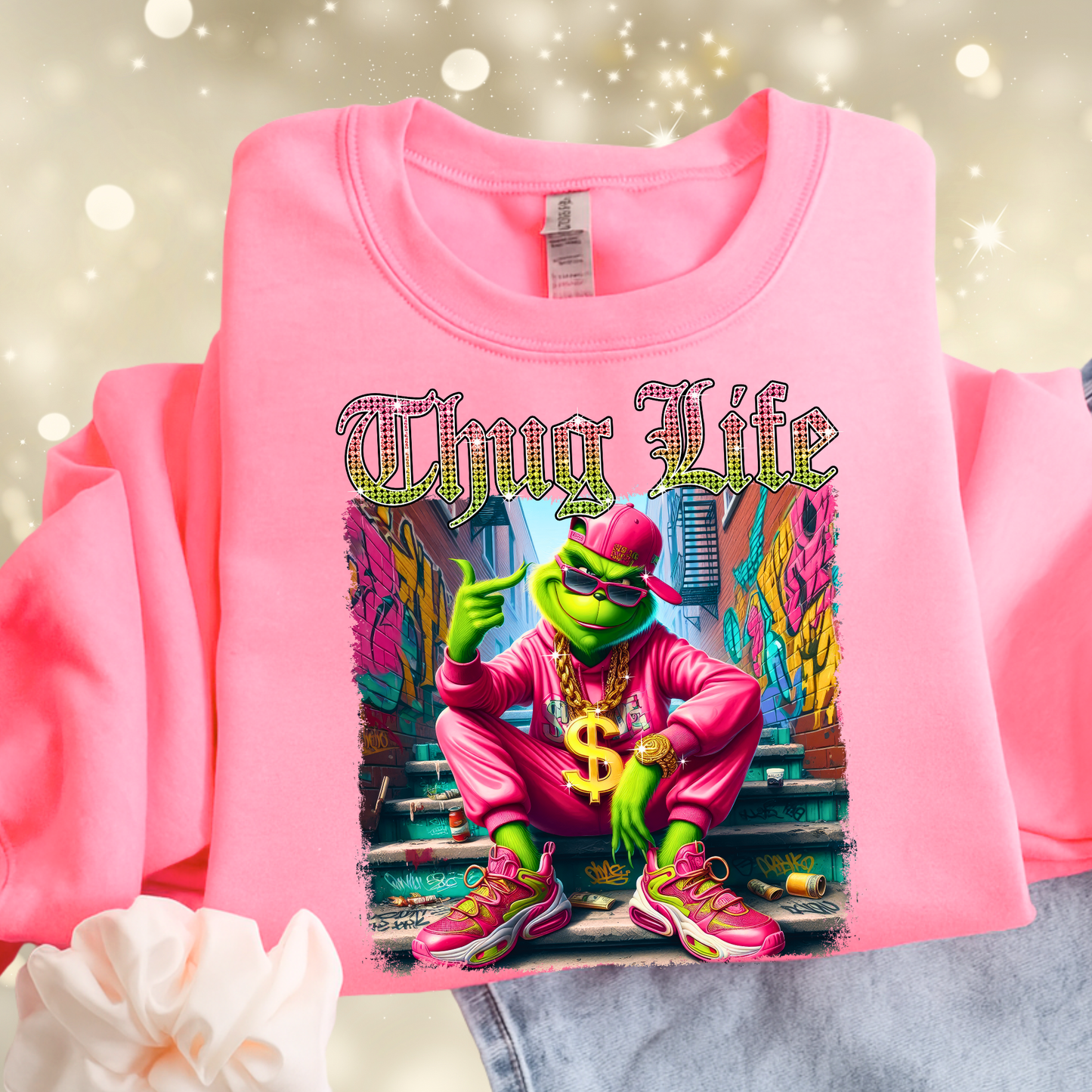 Bright pink sweatshirt flat lay showing Thug Life street style graphic with colorful urban artwork.