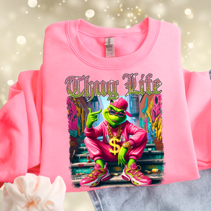 Bright pink sweatshirt flat lay showing Thug Life street style graphic with colorful urban artwork.