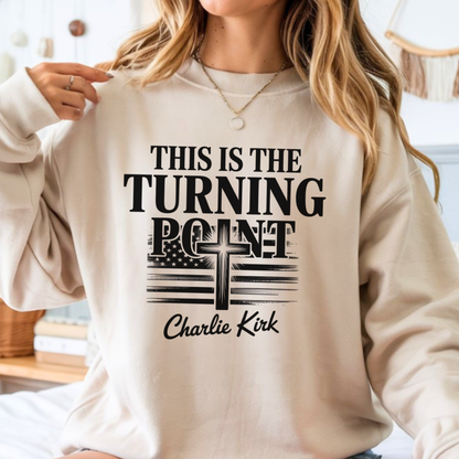 Indoor lifestyle image of woman wearing sand sweatshirt with “This Is the Turning Point” Christian cross flag design