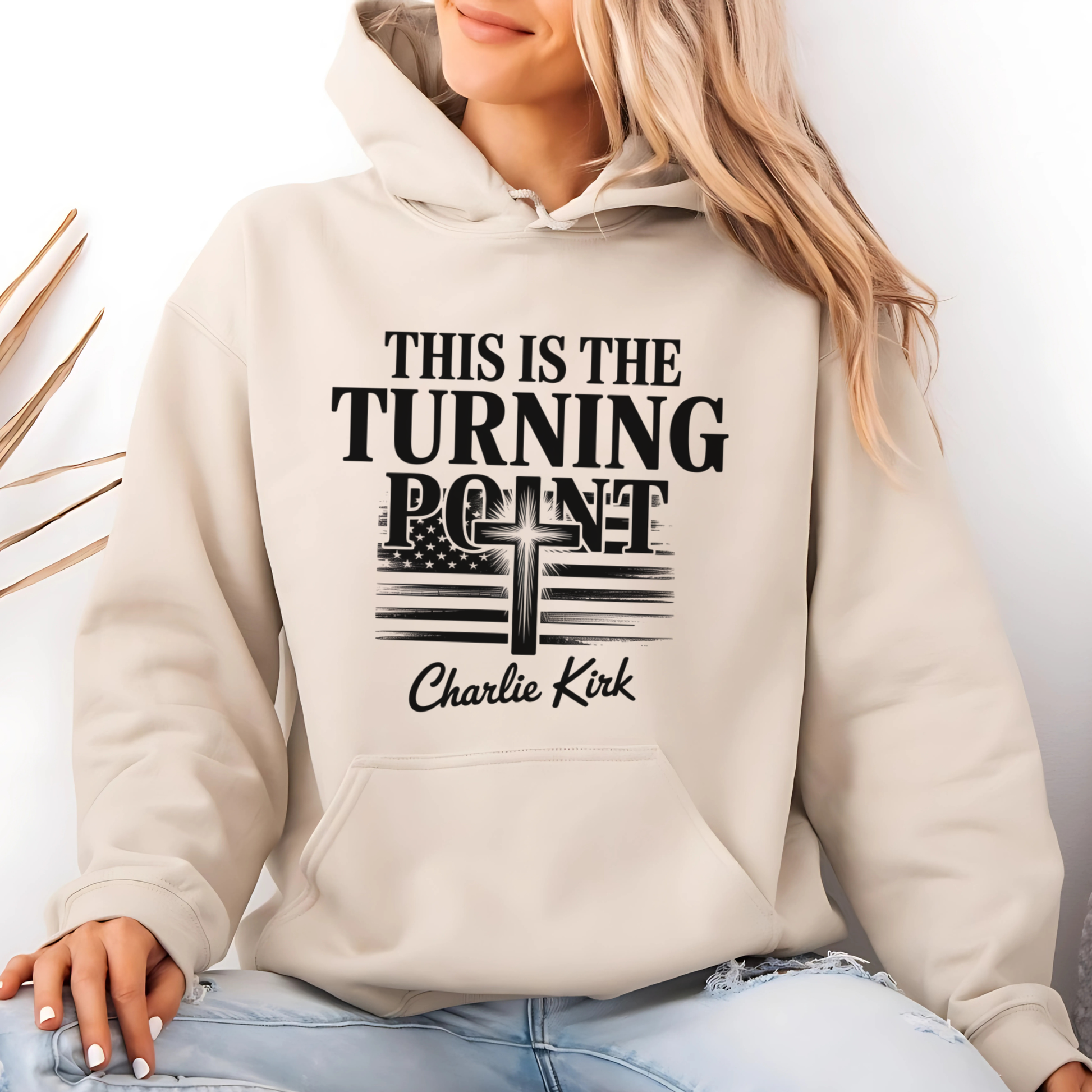 Studio lifestyle photo of sand hoodie with Turning Point faith and freedom cross graphic