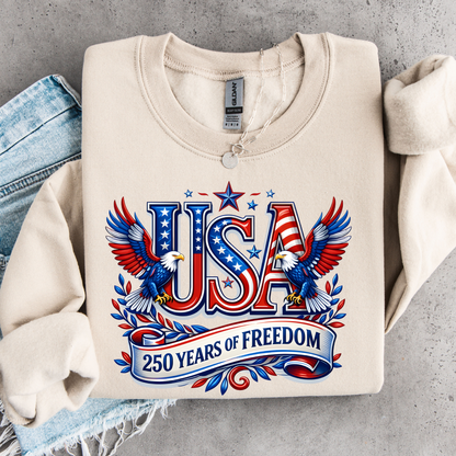 Beige sweatshirt with 'USA 250 Years of Freedom' design on a gray surface
