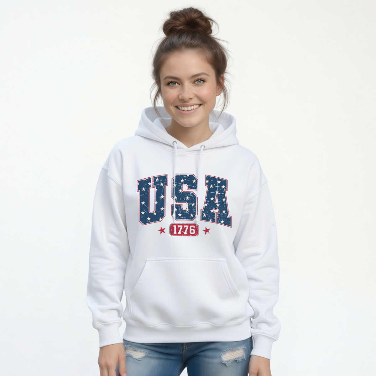 Smiling woman in a white pullover hoodie with a navy USA graphic filled with white stars and red 1776 lettering