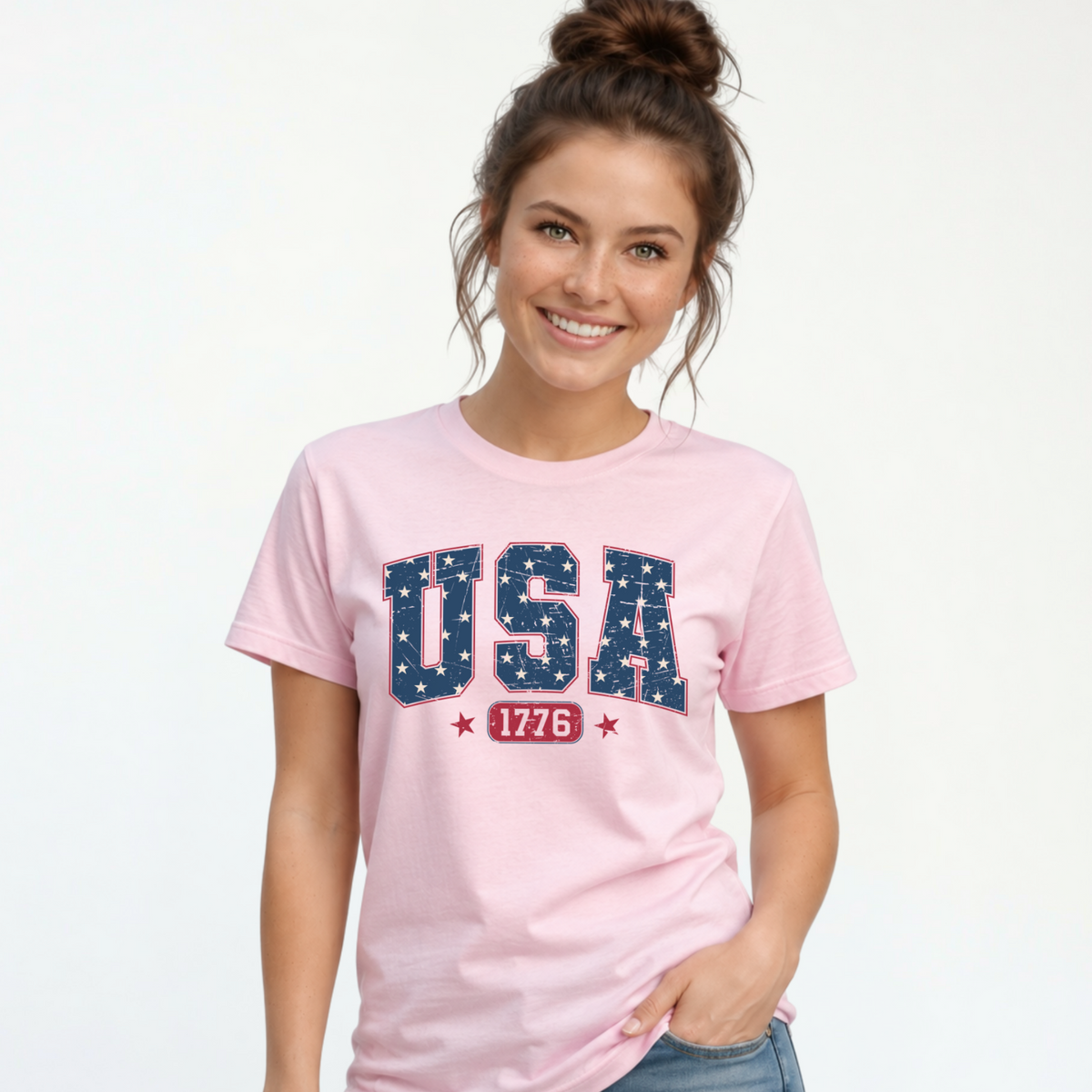 Smiling woman in a light pink T-shirt with a navy USA graphic filled with white stars and red 1776 lettering