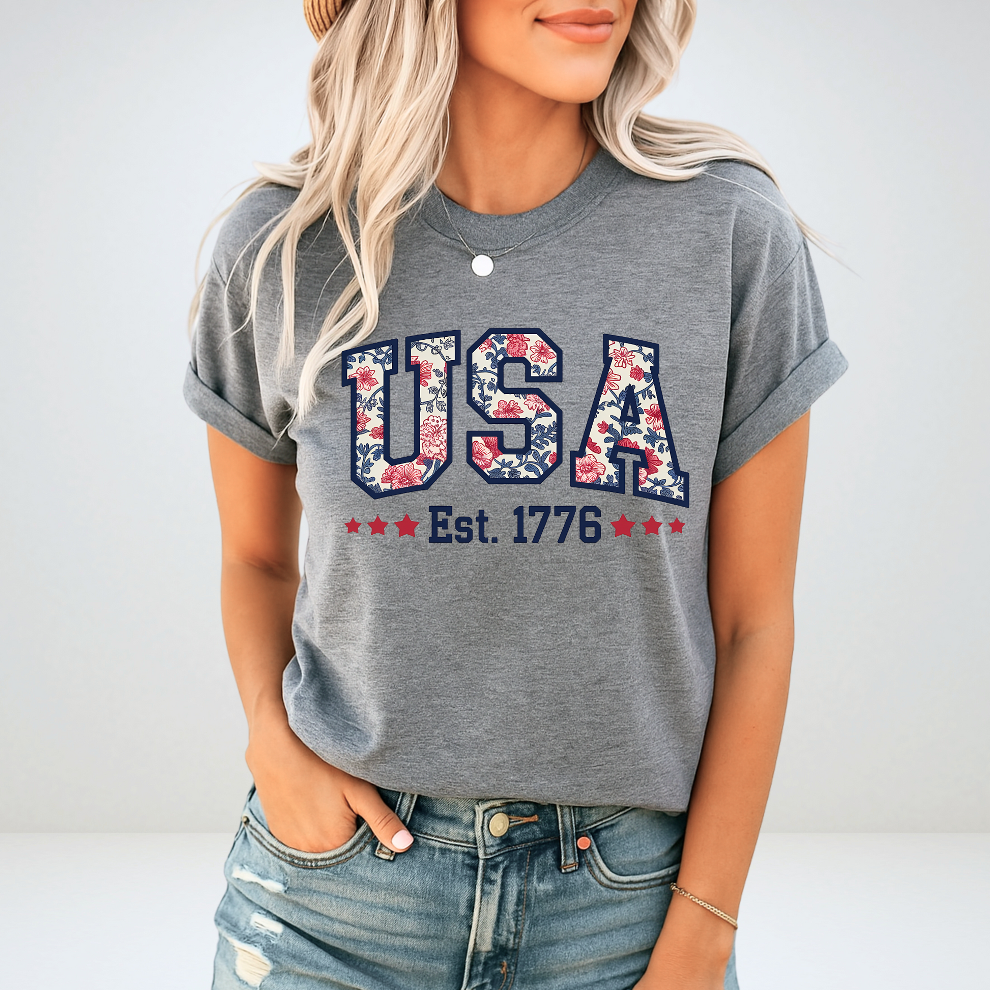 Woman wearing a gray USA Est. 1776 floral patriotic T-shirt – casual fit with rolled sleeves, styled for summer.

