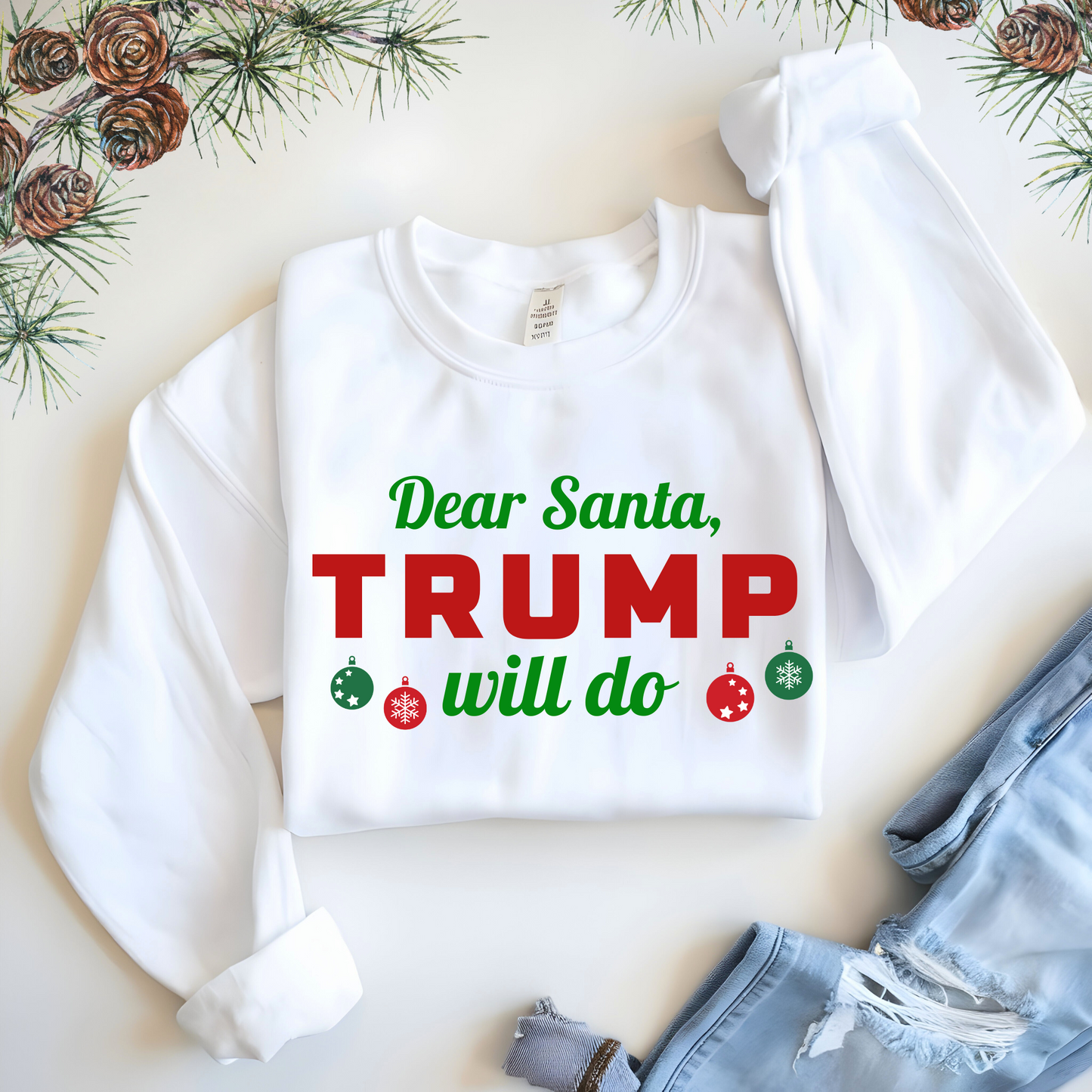 Folded white sweatshirt with festive conservative design laid flat with denim shorts and pine décor