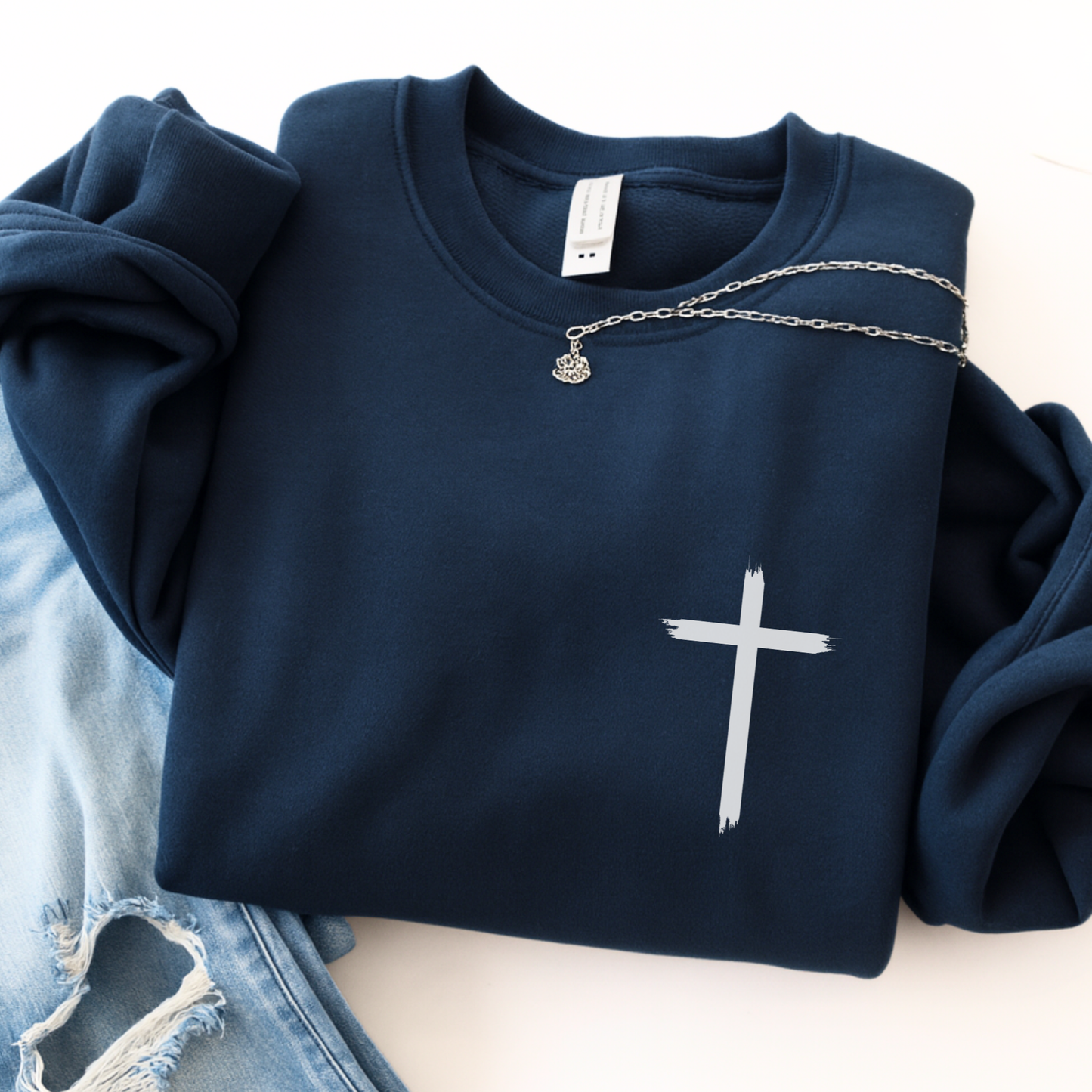 Navy blue sweatshirt with a white cross design on a light background