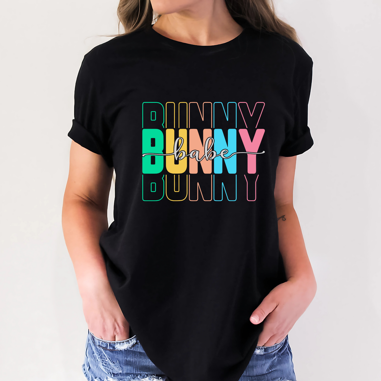 Trendy Bunny Babe graphic t-shirt with colorful pastel typography, perfect for Easter outfits, spring fashion, and casual wear. Soft cotton tee for women.