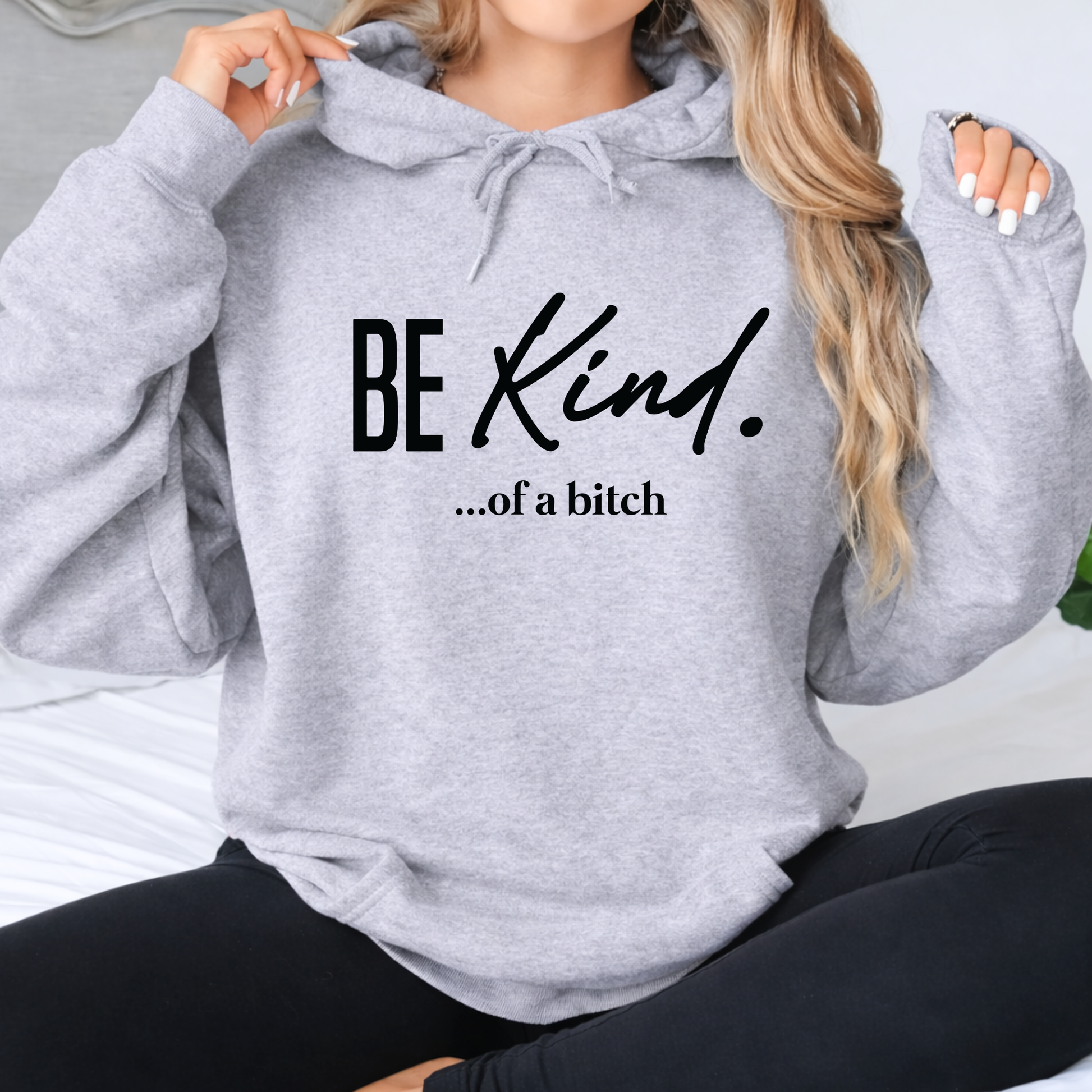 Gray hoodie with 'BE KIND...of a bitch' text worn by a person.