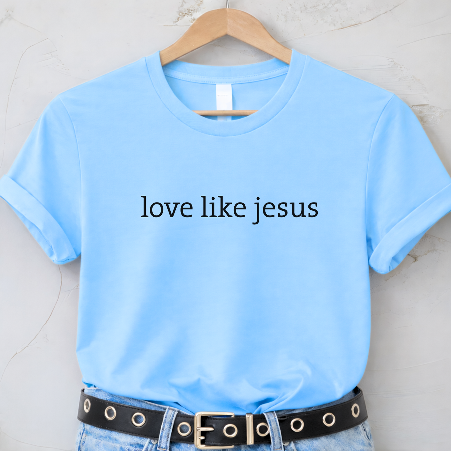 Light blue t-shirt with 'love like jesus' text on a hanger.