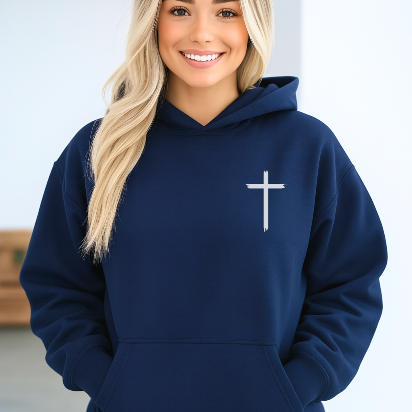 Person wearing a navy blue hoodie with a white cross on a light background