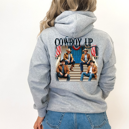 A white hoodie with a graphic print of cowboys seated on a porch with American flags and the text 'Cowboy Up' on the back and a front-left chest portrait of a cowboy with 'Cowboy Up' script.