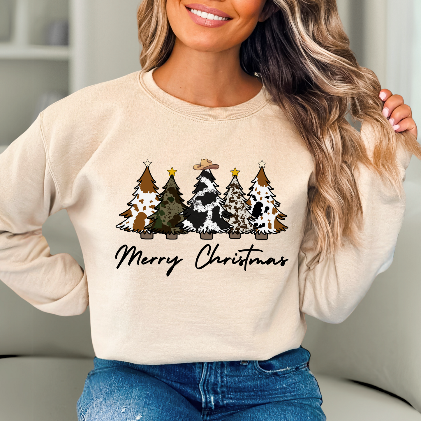 Woman wearing a beige sweatshirt with Christmas tree design and 'Merry Christmas' text.