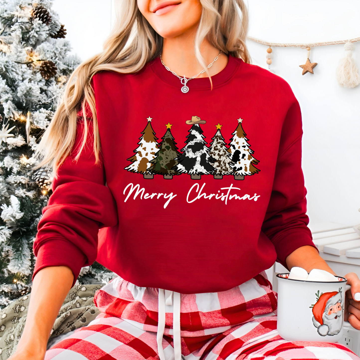 Person wearing a red Christmas-themed sweatshirt with trees and 'Merry Christmas' text, holding a mug.