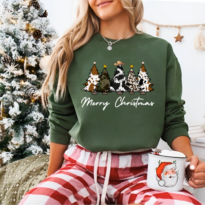 Person wearing a green 'Merry Christmas' sweater with tree designs, holding a Santa mug, in front of a decorated Christmas tree.