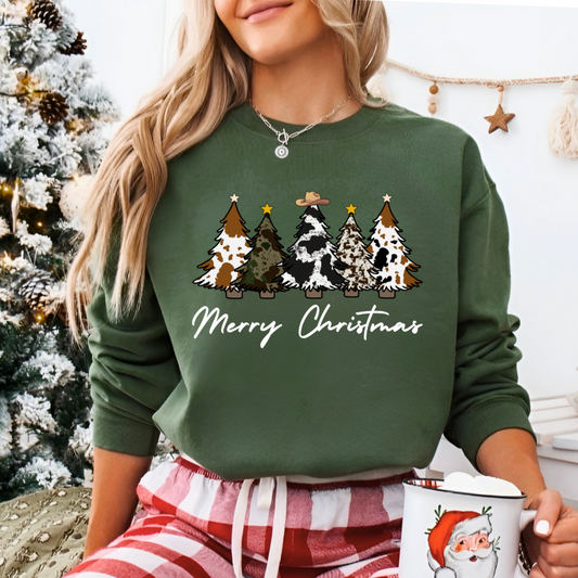 Person wearing a green 'Merry Christmas' sweater with tree designs, holding a Santa mug, in front of a decorated Christmas tree.