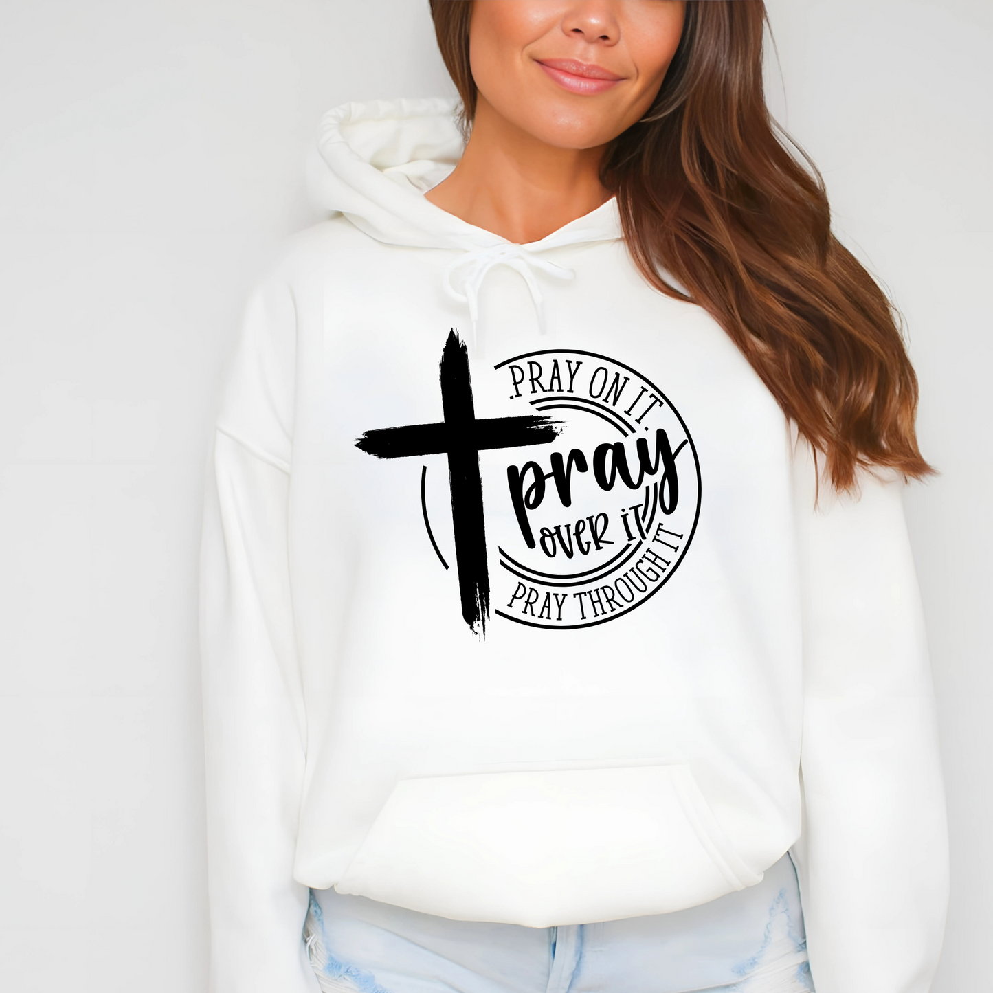 Close-up of a white hoodie with a white cross and ‘Pray Over It’  quote.
