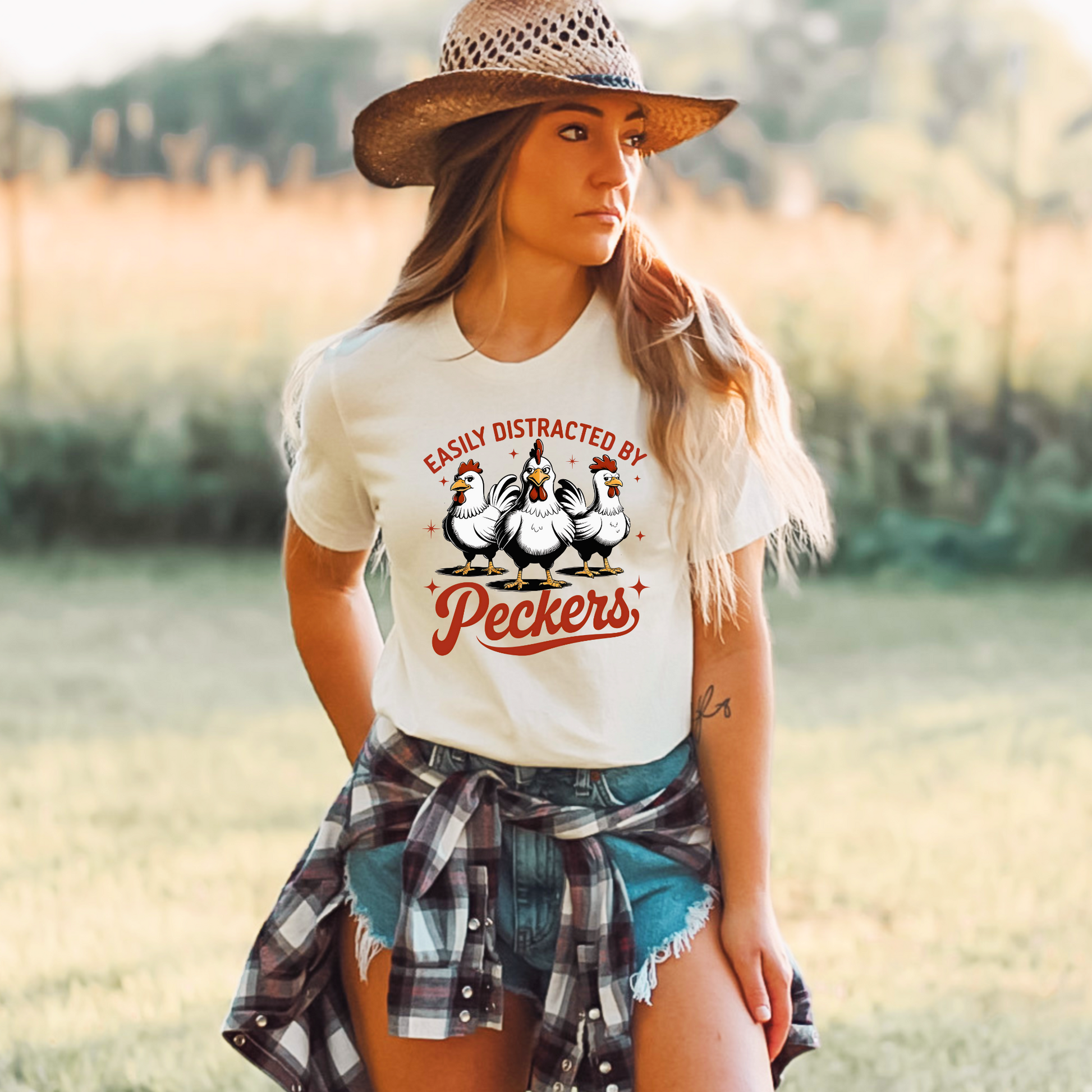  Woman wearing a White T-shirt with "Easily Distracted by Peckers" text and three funny chickens design. Perfect for chicken lovers and humor enthusiasts