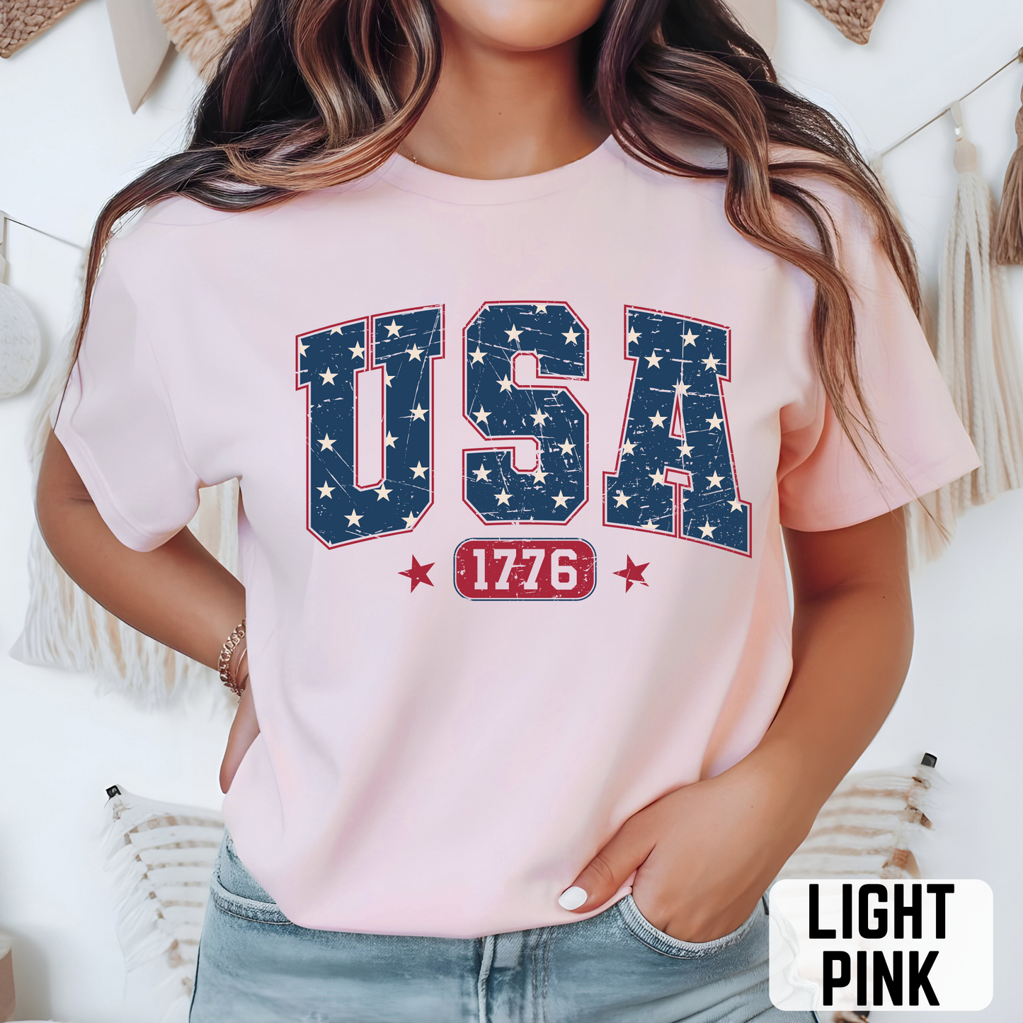 Woman wearing sport gray USA 1776 graphic T-shirt with distressed navy stars and red lettering, casual patriotic outfit