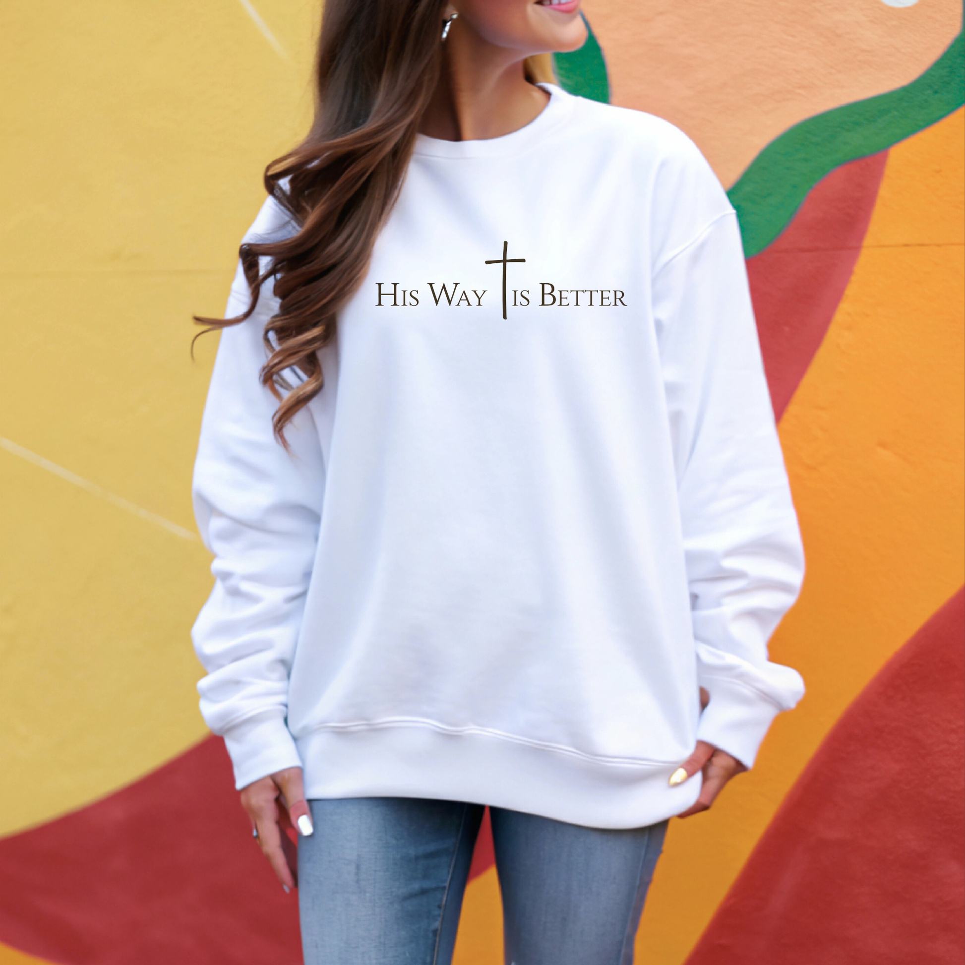 Woman wearing white “His Way Is Better” cross sweatshirt holding  outdoors