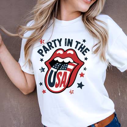 Happy woman wearing white “Party in the USA” shirt with bold graphic design. Patriotic lips with flag tongue surrounded by stars. Great for summer, 4th of July parties, and patriotic fashion.

