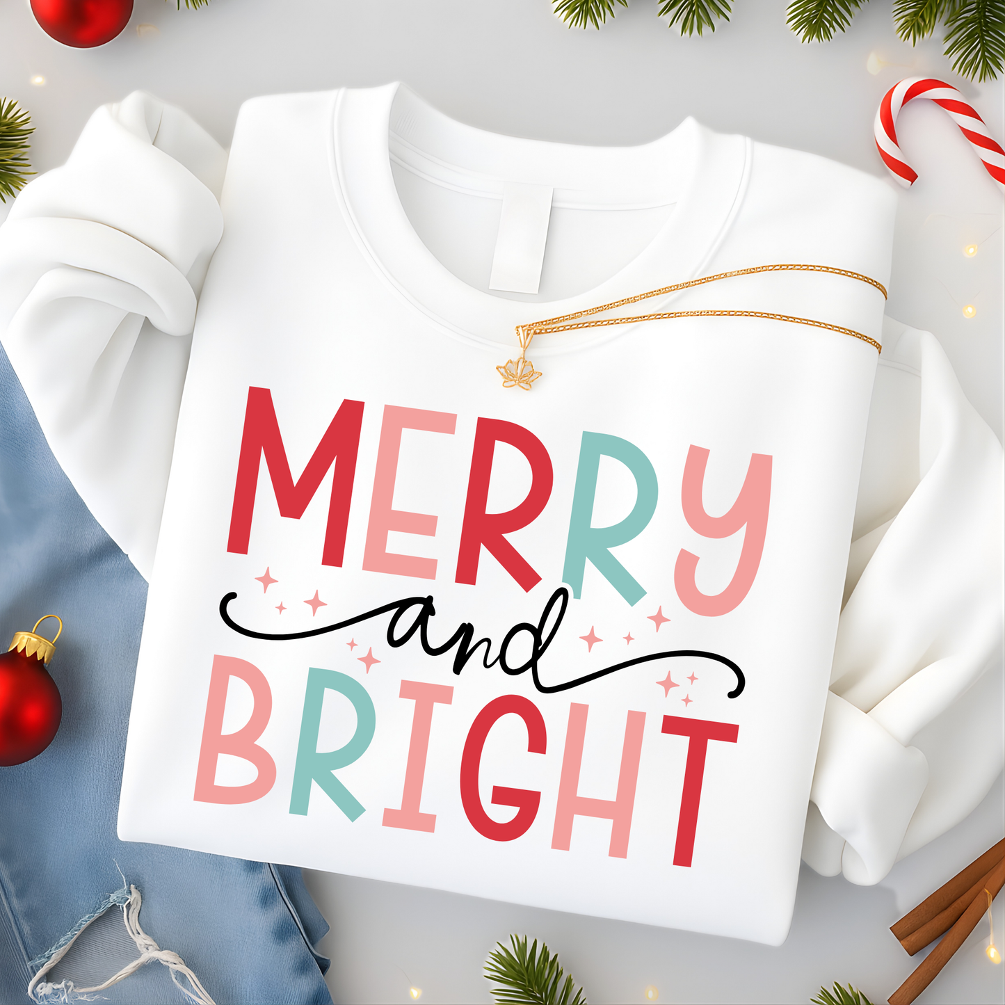 White sweatshirt with 'Merry and Bright' text surrounded by Christmas decorations on a light gray background