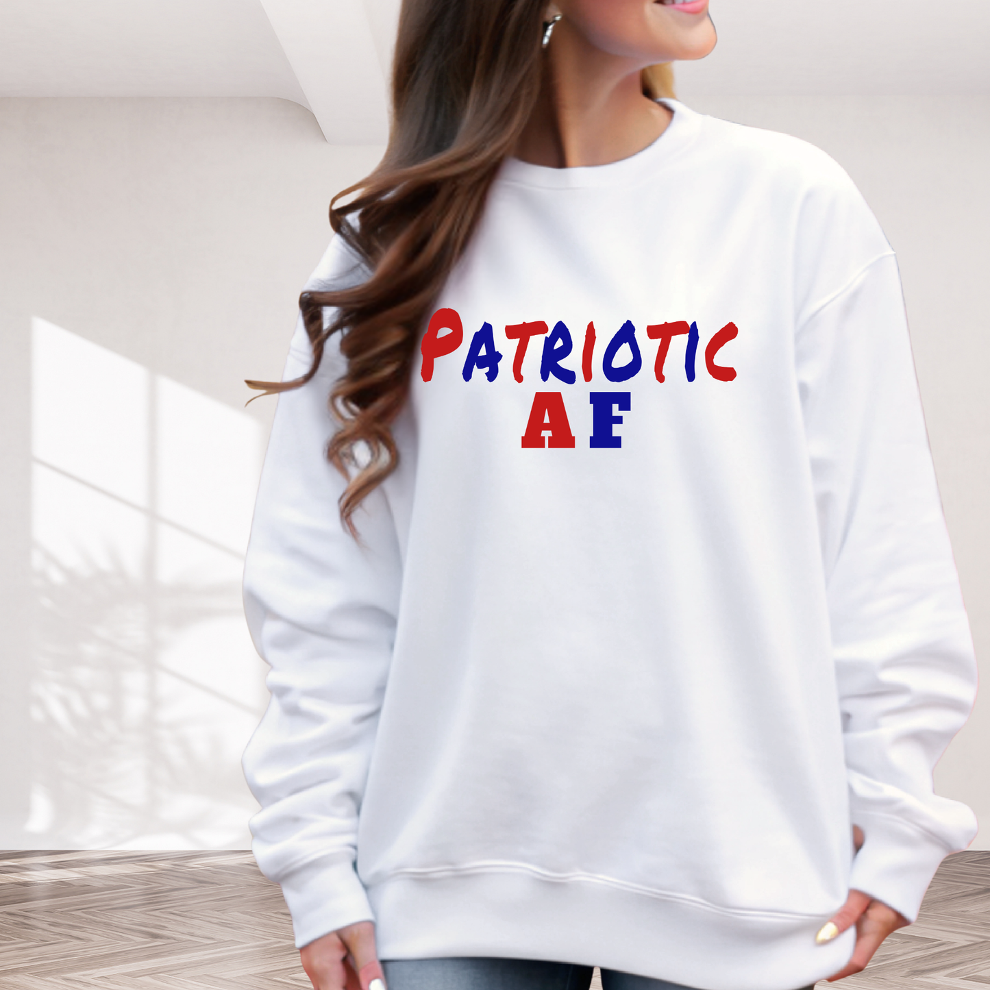 White sweatshirt with 'Patriotic AE' text in red, blue, and yellow worn by a person indoors.