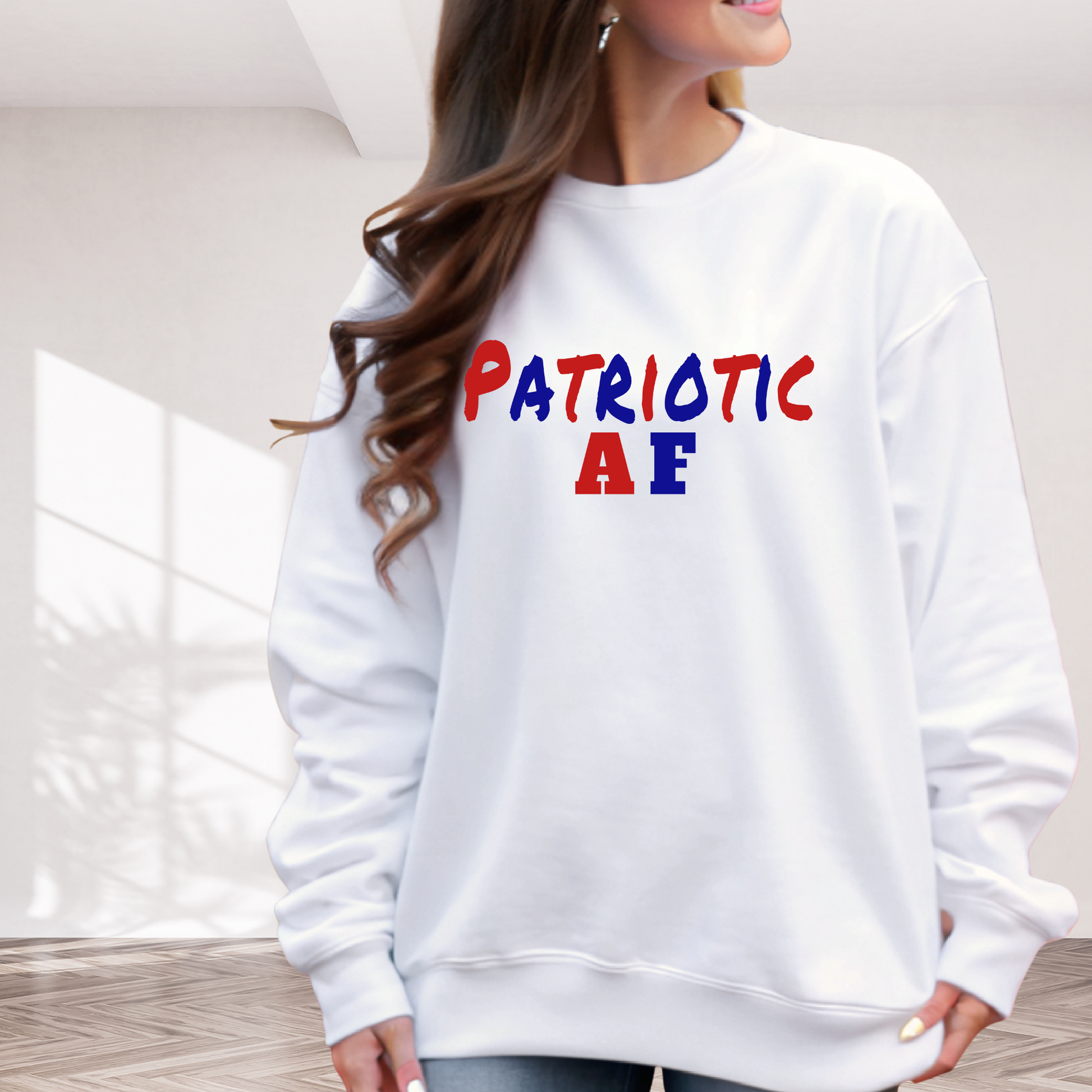 White sweatshirt with 'Patriotic AE' text in red, blue, and yellow worn by a person indoors.