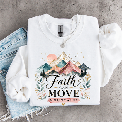 White sweatshirt with mountain design and 'Faith Can Move Mountains' text on a concrete surface.