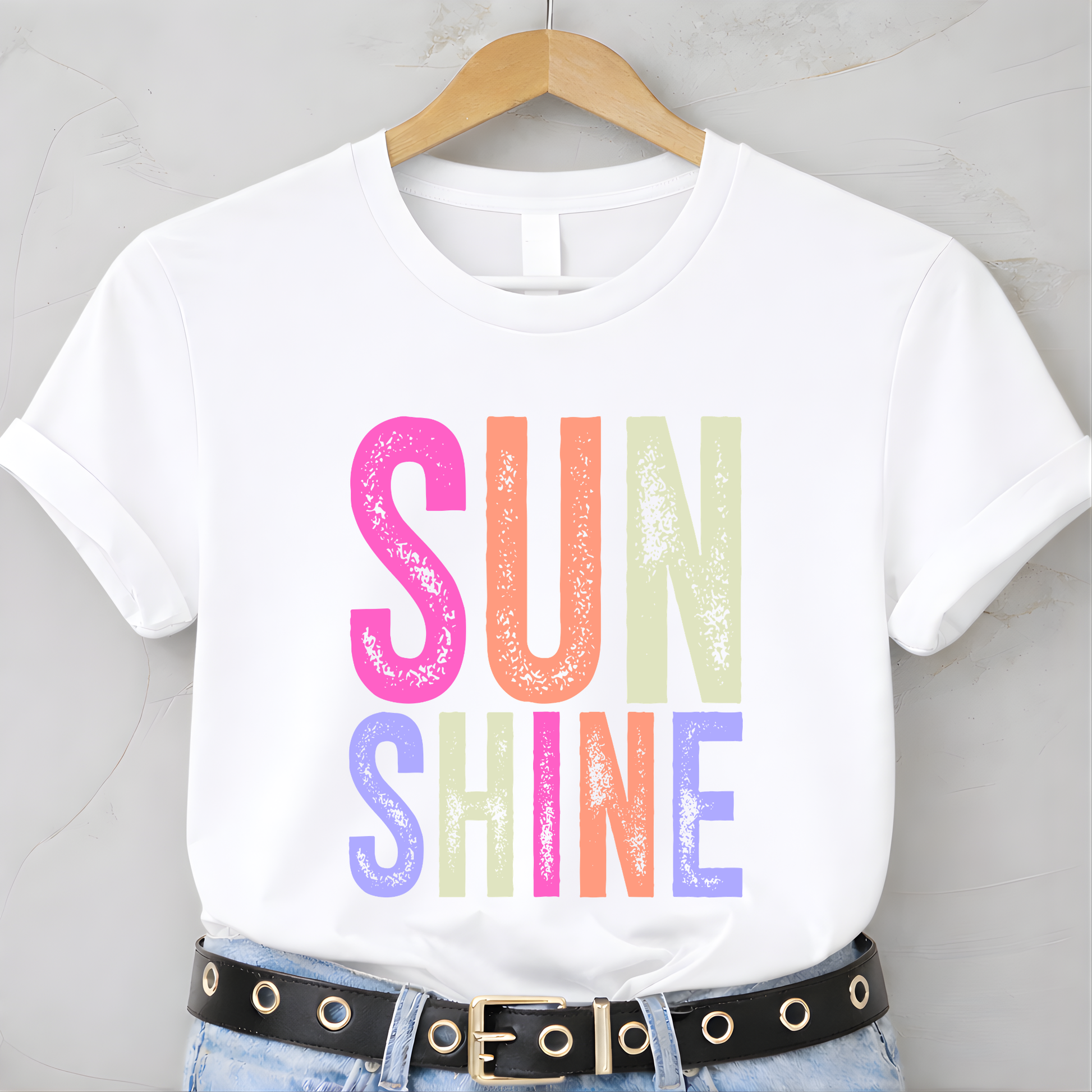 White t-shirt with 'SUNSHINE' in colorful letters on a hanger.