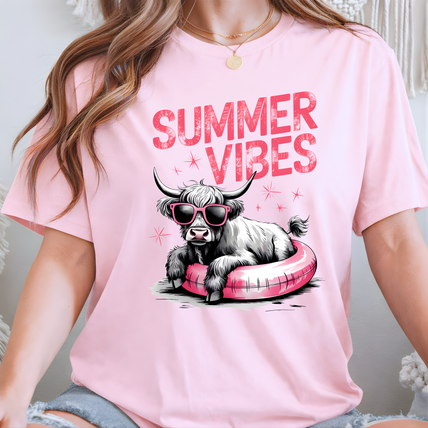 Woamn wearing a pink t-shirt with a highland cow graphic and 'Summer Vibes' text.