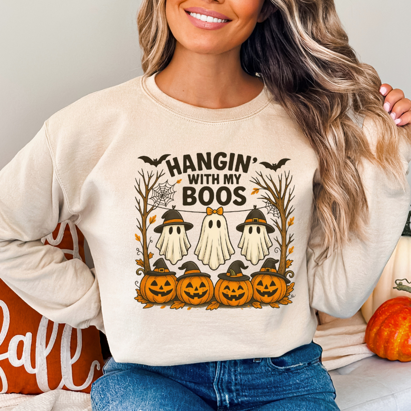 woman wearing a sand Hangin’ With My Boos Halloween sweatshirt featuring ghosts, pumpkins, and bats. Casual unisex fit, perfect for fall outings or Halloween parties.