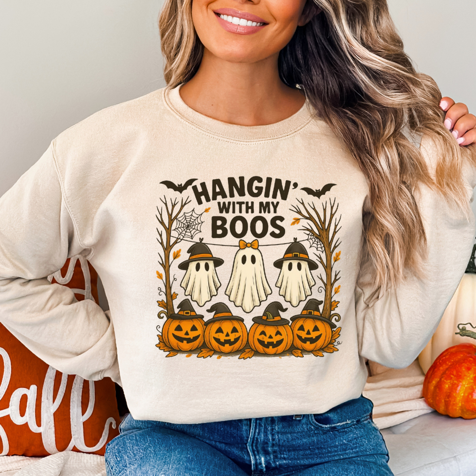 woman wearing a sand Hangin’ With My Boos Halloween sweatshirt featuring ghosts, pumpkins, and bats. Casual unisex fit, perfect for fall outings or Halloween parties.