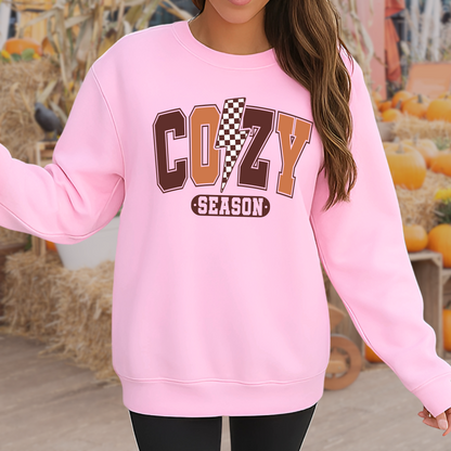 Woman in light pink Cozy Season sweatshirt standing in a fall pumpkin patch